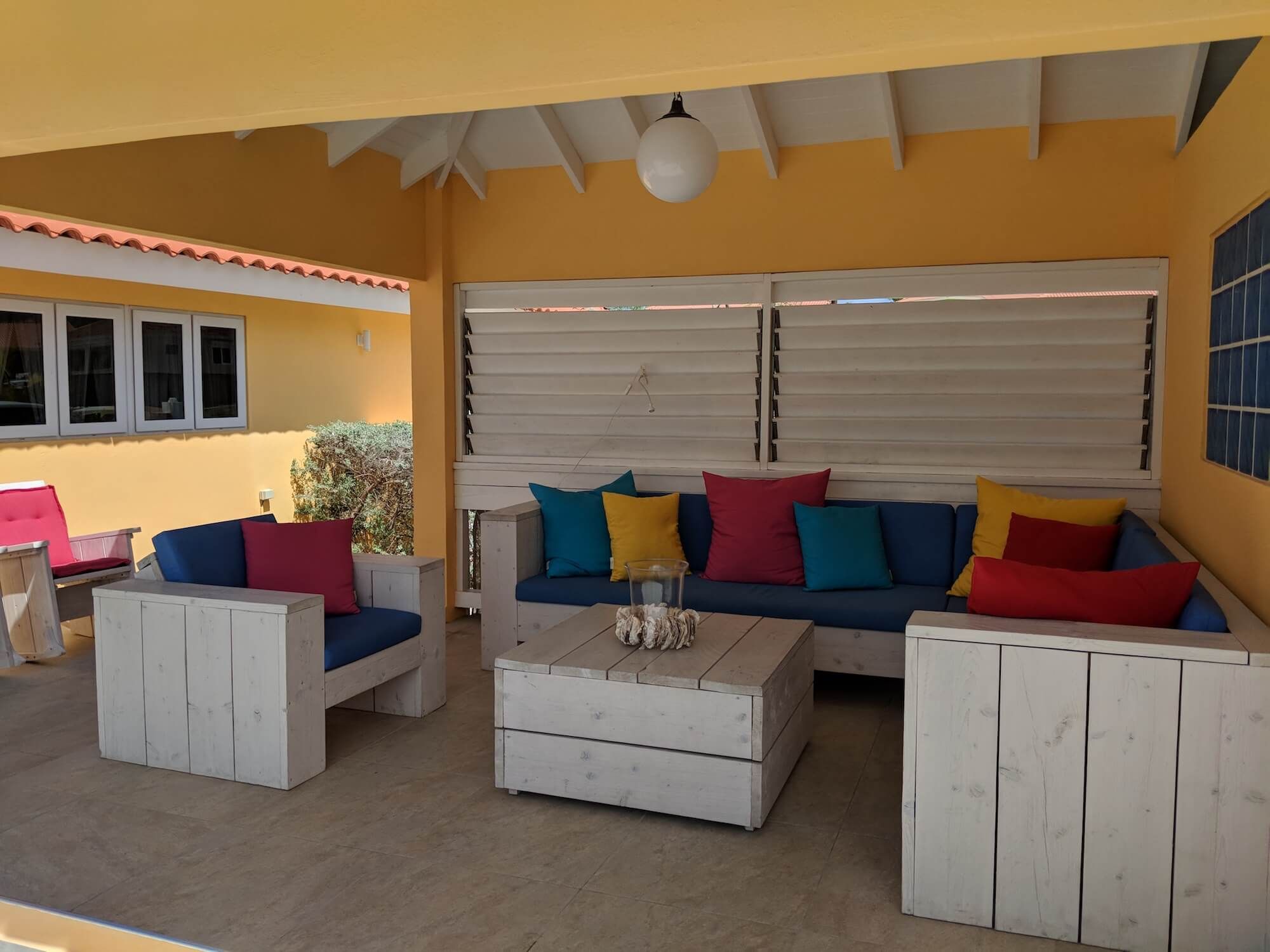 De ruime loungeporch met banken, fauteuils en een hangmat