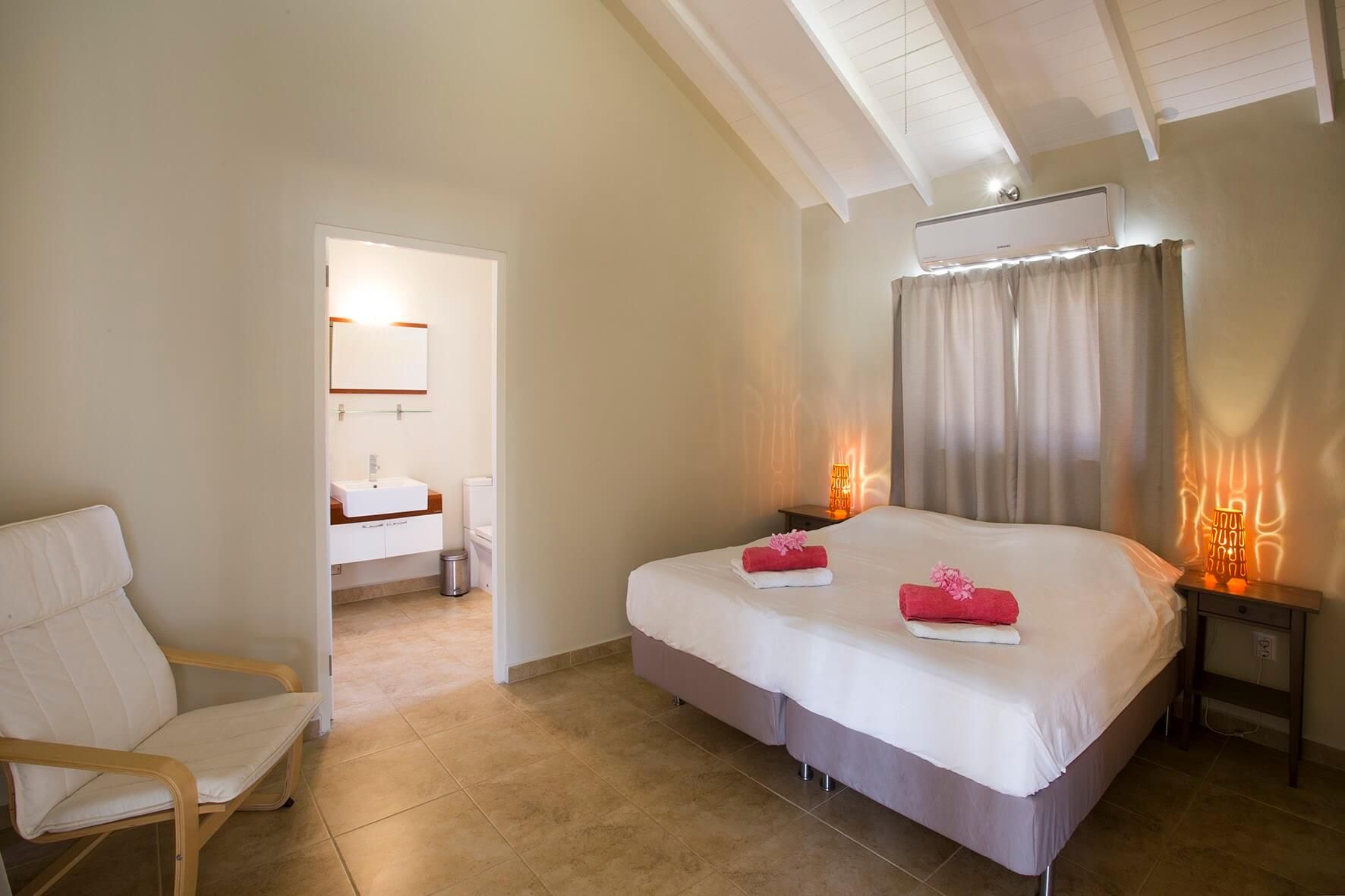 De hoofdslaapkamer met tweepersoonsbed, handdoeken op het bed en de deur naar de ensuite badkamer
